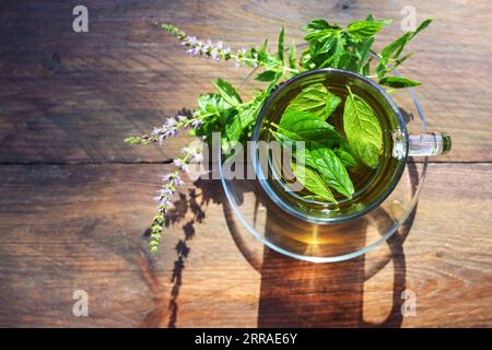 Tisane à partir de feuilles de menthe poivrée fraîches et de fleurs dans une tasse en verre sur une table en bois rustique, vue à grand angle d'en haut, espace de copie, foyer sélectionné, n Banque D'Images