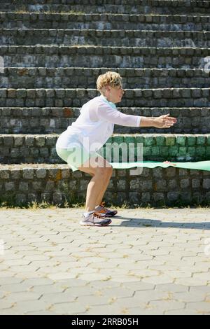 Femme mature dans la formation de sportswear en extérieur. Faire des exercices d'étirement et d'échauffement Banque D'Images