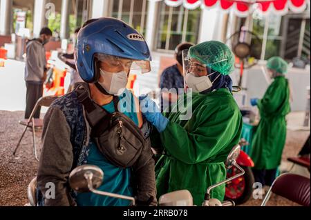 210823 -- YOGYAKARTA, le 23 août 2021 -- Un homme sur sa moto reçoit une dose du vaccin COVID-19 lors d'une vaccination au volant à Yogyakarta, Indonésie, le 23 août 2021. À ce jour, au moins 32,04 millions de personnes en Indonésie ont reçu deux injections de vaccins, et 57,77 millions ont reçu la première dose, a déclaré lundi le ministère indonésien de la Santé. Le gouvernement vise à vacciner 208,2 millions de personnes. Photo de /Xinhua INDONESIA-COVID-19-VACCINATION Supriyanto PUBLICATIONxNOTxINxCHN Banque D'Images