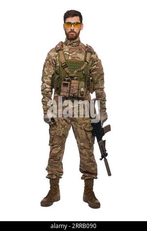 Soldat masculin sérieux avec mitrailleuse à la main, regardant la caméra en studio. Vue de face d'un soldat fort en armure de corps posant, tenant l'arme, isolé sur fond blanc. Concept de force militaire. Banque D'Images