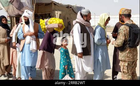 210828 -- CHAMAN, le 28 août 2021 -- Un soldat pakistanais vérifie les documents de personnes avant de les laisser entrer au Pakistan à un point de passage frontalier entre le Pakistan et l'Afghanistan, dans le sud-ouest du Pakistan, Chaman, le 27 août 2021. Le Pakistan a facilité l ' évacuation de personnes d ' Afghanistan, y compris de membres de la communauté internationale. Le ministre fédéral pakistanais de l'information et de la radiodiffusion, Chaudhry Fawad Hussain, a déclaré mardi aux médias que plus de 3 400 19 000 personnes avaient été évacuées par avion, tandis qu'environ 500 000 personnes avaient traversé les frontières pour se rendre au Pakistan. Str/Xinhu Banque D'Images