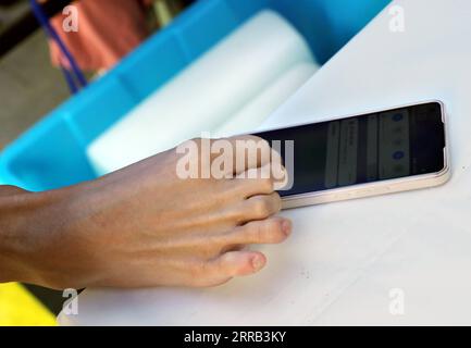 210830 -- SHANGHAI, 30 août 2021 -- Peng Chao contrôle un téléphone portable avec son pied pour montrer son code de santé et ses données d'historique de voyage pour les mesures de prévention des épidémies alors qu'il entre à l'Université de Tongji dans l'est de la Chine à Shanghai, le 29 août 2021. Alors que l'Université de Tongji a accueilli ses nouveaux étudiants dimanche, Peng Chao, un nouveau venu prêt pour des études de troisième cycle, est arrivé au comptoir d'inscription pour passer par le processus, commençant sa poursuite d'une maîtrise. Peng a été mutilé dans un accident et a perdu ses deux bras à l'âge de 6 ans. Au lieu d'être renversé par le revers, Peng a surmonté les difficultés et o Banque D'Images