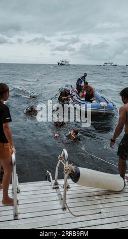 Plongeurs nageant de retour à la vie à bord d'un bateau, revenant d'une plongée à Richelieu Rock, île de Similan, Thaïlande. Banque D'Images