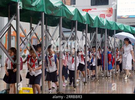 210913 -- SHANGHAI, le 13 septembre 2021 -- les élèves font la queue sous l'abri d'un auvent amovible après les cours dans une école primaire du district de Huangpu, Shanghai dans l'est de la Chine, le 13 septembre 2021. Shanghai a ordonné aux jardins d'enfants, aux écoles primaires et secondaires de suspendre les cours du lundi après-midi au mardi alors que la ville se prépare à de fortes pluies et des vents forts dus au typhon Chanthu. CHINA-SHANGHAI-TYPHOON-PENDED CN LIUXYING PUBLICATIONXNOTXINXCHN Banque D'Images