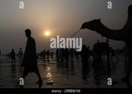 210913 -- KARACHI, 13 septembre 2021 -- la photo prise le 13 septembre 2021 montre la silhouette d'un propriétaire de chameau alors qu'il attend des clients sur une plage au coucher du soleil dans la ville portuaire de Karachi, dans le sud du Pakistan. PAKISTAN-KARACHI-BEACH-VIE QUOTIDIENNE AhmadxKamal PUBLICATIONxNOTxINxCHN Banque D'Images