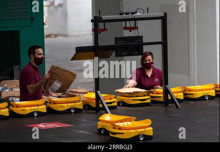 210921 -- ATHÈNES, le 21 septembre 2021 -- les employés du fournisseur national de services postaux grec Hellenic Post ELTA travaillent en Grèce avec un système robotique de fabrication chinoise pour trier les articles de courrier dans les installations d'ELTA à Kryoneri, une banlieue nord d'Athènes, Grèce, le 14 septembre 2021. L'ELTA en grec a commencé à utiliser un système robotique de fabrication chinoise pour trier les articles de courrier, dans le but d'accélérer le processus et d'améliorer le service aux clients. Le système automatisé entièrement numérisé est développé par la Chine Zhejiang LiBiao robot Co., Ltd Depuis mi-août, une flotte de 55 minuscules robots jaunes a rejoint les employés Banque D'Images