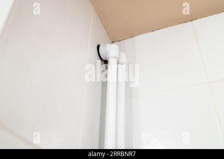 entrée de tuyaux en polypropylène au plafond de la salle de bain sur le mur recouvert de carreaux de céramique Banque D'Images