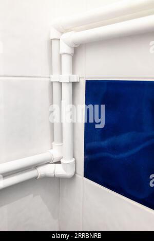 nouveaux tuyaux en polypropylène blanc connectés dans le coin de la salle de bain sur le mur recouvert de carreaux de céramique Banque D'Images