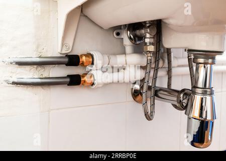raccordement de tuyaux en polypropylène, métal flexible et plastique sous évier dans la salle de bain Banque D'Images