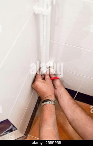 le plombier essaie le coude sur le tuyau de polypropylène dans le coin de la salle de bain pendant l'installation de la nouvelle plomberie Banque D'Images