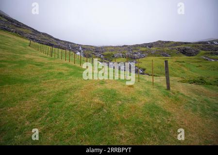 Cascades d'eau sur une pente au-dessus du village de Tjørnuvik, dans les îles Féroé. Banque D'Images