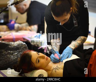 211025 -- VARSOVIE, le 25 octobre 2021 -- Une femme se fait tatouer lors de la 8e convention de tatouage de Varsovie à Varsovie, Pologne, le 24 octobre 2021. Str/Xinhua POLOGNE-VARSOVIE-TATOUAGE CONVENTION Stringer PUBLICATIONxNOTxINxCHN Banque D'Images