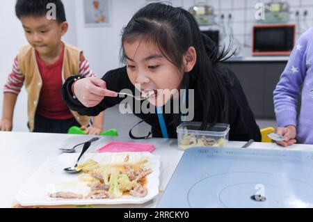 211110 -- FOSHAN, le 10 novembre 2021 -- Une fille goûte le plat cuisiné par son équipe pendant le cours de cuisine au centre de formation Little Chef de l'école primaire de Xishan dans le district de Shunde de la ville de Foshan, province du Guangdong dans le sud de la Chine, le 9 novembre 2021. L’école primaire Xishan à Shunde a mis en place un centre de formation Little Chef depuis septembre de cette année sur son campus scolaire en coopération avec l’école de formation professionnelle Shunde Fengchu, offrant aux étudiants un cours de cuisine de 45 minutes après l’école tous les jours. Des instructeurs de cuisine professionnels, en collaboration avec des enseignants, donnent des cours de cuisine Banque D'Images