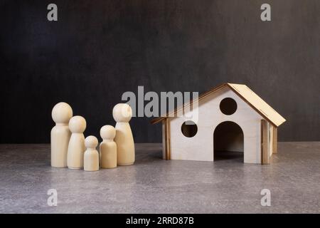 Figurines en bois d'une famille et une carte de crédit près d'une maison blanche. Le concept d'un prêt au logement pour une jeune famille nombreuse Banque D'Images