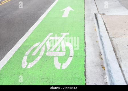 Piste cyclable vide de couleur verte courant le long d'une rue dans un quartier du centre-ville Banque D'Images