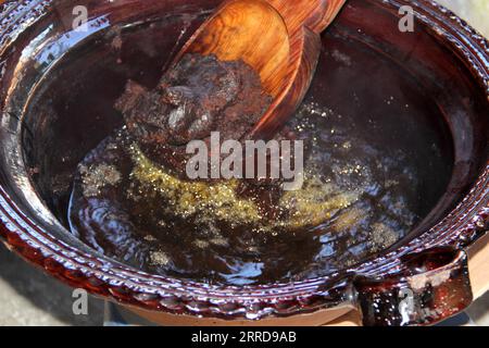 Préparation de taupe rouge, un plat typiquement mexicain dans un pot en argile avec une cuillère en bois géante sur le feu d'un poêle avec tous les ingrédients intégrés Banque D'Images