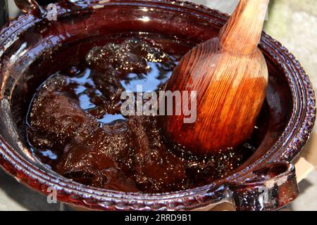 Préparation de taupe rouge, un plat typiquement mexicain dans un pot en argile avec une cuillère en bois géante sur le feu d'un poêle avec tous les ingrédients intégrés Banque D'Images