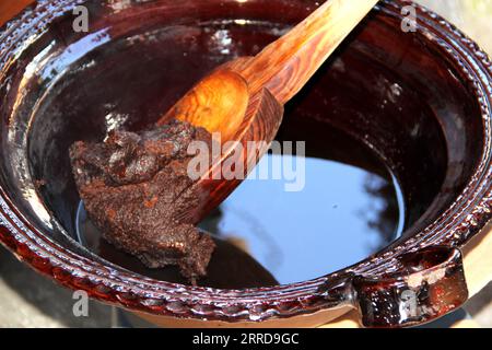 Préparation de taupe rouge, un plat typiquement mexicain dans un pot en argile avec une cuillère en bois géante sur le feu d'un poêle avec tous les ingrédients intégrés Banque D'Images