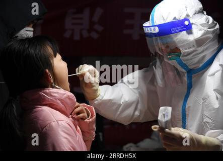 211225 -- XI AN, le 25 décembre 2021 -- Un travailleur médical prélève un échantillon d'écouvillon d'un enfant pour un test d'acide nucléique sur un site d'échantillonnage dans le district de Lianhu de Xi an, dans la province du Shaanxi du nord-ouest de la Chine, le 25 décembre 2021. Xi an a lancé une nouvelle série de tests d’acides nucléiques complets à partir de 12:00 heures du matin samedi, depuis que de nouveaux cas confirmés de COVID-19 transmis localement ont été signalés. CHINA-SHAANXI-XI AN-COVID-19-ACIDE NUCLÉIQUE TEST CN LIXYIBO PUBLICATIONXNOTXINXCHN Banque D'Images