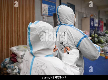 220105 -- XI AN, le 5 janvier 2022 -- Un volontaire écrit le nom de Xu Kai sur son costume de protection à la cuisine partagée Deshan dans le district de Yanta de Xi an, dans la province du Shaanxi au nord-ouest de la Chine, le 5 janvier 2022. Situé dans le district de Yanta de Xi an, la cuisine partagée Deshan a été gérée comme une cuisine anti-cancer , offrant la commodité pour les patients atteints de cancer et leurs familles pour cuisiner des repas. Xu Kai, fondateur de la cuisine partagée, a transformé cette cuisine anti-cancer en cuisine de lutte contre l’épidémie après que la ville ait été frappée par la récente résurgence du COVID-19. Jusqu’à présent, plus de 30 bénévoles se sont joints à la nourriture Banque D'Images