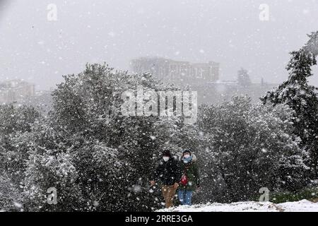 220124 -- ATHÈNES, le 24 janvier 2022 -- les gens marchent dans la neige au pied de l'Acropole à Athènes, Grèce, le 24 janvier 2022. Un front froid intense balayait la Grèce lundi, provoquant des perturbations dans les transports et des coupures de courant pendant plusieurs heures dans de nombreuses régions, ont indiqué les autorités locales. GRÈCE-ATHÈNES-NEIGE MariosxLolos PUBLICATIONxNOTxINxCHN Banque D'Images