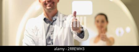 Radiologue masculin et patiente montrant les pouces près du scanner CT à l'hôpital. Banque D'Images