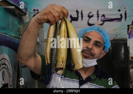 220420 -- GAZA, le 20 avril 2022 -- Un palestinien prépare du poisson fumé sur un marché devant Aïd al-Fitr dans la ville de Rafah, dans le sud de la bande de Gaza, le 20 avril 2022. Photo de /Xinhua MIDEAST-GAZA-RAFAH-EID AL-FITR-PRÉPARATION RizekxAbdeljawad PUBLICATIONxNOTxINxCHN Banque D'Images