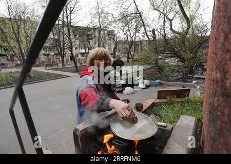 220422 -- MARIUPOL, le 22 avril 2022 -- Une femme cuisine en plein air dans la ville portuaire de Mariupol, le 21 avril 2022. Le président russe Vladimir Poutine a ordonné jeudi un blocus de l'usine Azovstal dans la ville portuaire de Marioupol au lieu de l'attaquer, ont rapporté les médias locaux. Photo de /Xinhua RUSSIA-UKRAINE-CONFLICT-MARIUPOL Victor PUBLICATIONxNOTxINxCHN Banque D'Images