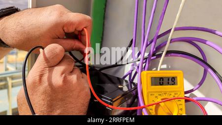 mains d'un électricien vérifiant avec un polymètre la tension et l'installation correcte de l'équipement Banque D'Images