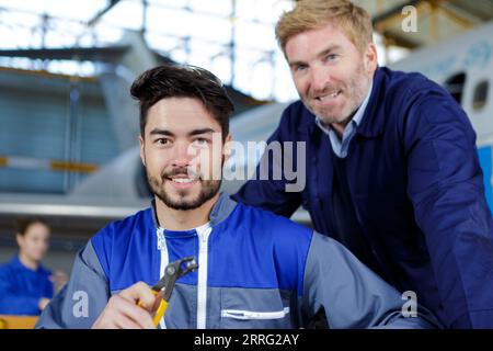 Deux mécaniciens travaillant sur un petit avion dans un hangar Banque D'Images