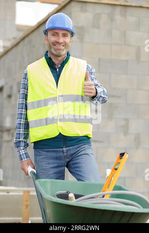 constructeur transportant des blocs sur une brouette sur le chantier de construction Banque D'Images