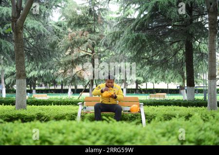 220509 -- ZHENGZHOU, le 9 mai 2022 -- le livreur Hua Qilong déjeune sur un banc à Zhengzhou, dans la province du Henan du centre de la Chine, le 8 mai 2022. Avec ses collègues, Hua Qilong, livreur de 25 ans à Zhengzhou, travaille en première ligne dans la prévention et le contrôle des épidémies et fournit de la nourriture, des médicaments et d'autres produits de première nécessité pour garantir les moyens de subsistance des populations. Je livre habituellement les médicaments et les commandes des hôpitaux d'abord, qui sont urgents pour les clients, a dit Hua. À partir de mai 4, à l'exception des zones de gestion fermées, d'autres zones du centre-ville de Zhengzhou ont été placées sous repos Banque D'Images