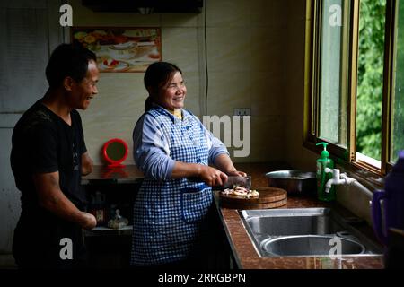 220516 -- ZUNYI, le 16 mai 2022 -- Jian Qin parle à son mari alors qu'elle se prépare à cuisiner chez elle dans le canton de Zhongguan, comté de Zheng an, province du Guizhou au sud-ouest de la Chine, le 12 mai 2022. Vivant au cœur des montagnes de Zunyi dans la province du Guizhou, Zhao Youliang et Jian Qin sont un couple handicapé. Zhao, âgé de 50 ans, a perdu ses mains à cause d'une amputation à un jeune âge, et Jian, âgée de 43 ans, a perdu la vue à cause du retard dans le traitement d'une maladie dans son enfance. Dans la vie quotidienne, Zhao aide sa femme à voir avec ses yeux, tandis que Jian aide son mari avec ses mains. Le couple h Banque D'Images