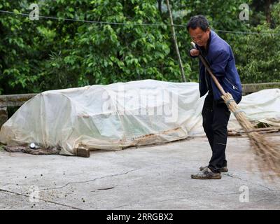 220516 -- ZUNYI, le 16 mai 2022 -- Zhao Youliang nettoie la cour de sa maison dans le canton de Zhongguan, comté de Zheng an, province du Guizhou au sud-ouest de la Chine, le 12 mai 2022. Vivant au cœur des montagnes de Zunyi dans la province du Guizhou, Zhao Youliang et Jian Qin sont un couple handicapé. Zhao, âgé de 50 ans, a perdu ses mains à cause d'une amputation à un jeune âge, et Jian, âgée de 43 ans, a perdu la vue à cause du retard dans le traitement d'une maladie dans son enfance. Dans la vie quotidienne, Zhao aide sa femme à voir avec ses yeux, tandis que Jian aide son mari avec ses mains. Le couple a été suppo Banque D'Images