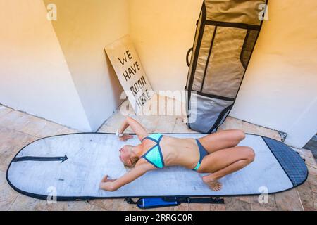 Jeune femme qui s'étire avant de surfer Banque D'Images