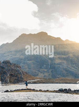 Homme debout près d'un lagon dans les montagnes des andes au coucher du soleil Banque D'Images