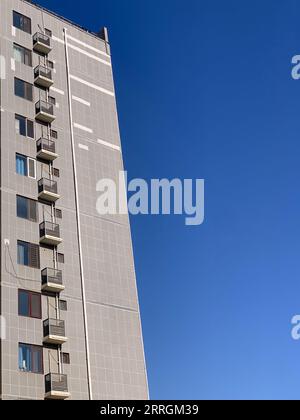 Un grand immeuble gris de grande hauteur avec balcons à ses étages supérieurs Banque D'Images