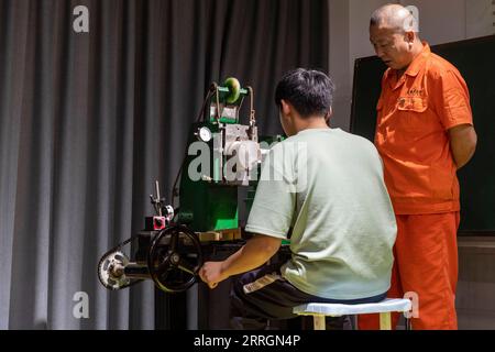 220527 -- XINMI, le 27 mai 2022 -- Cheng Yucai R guide un apprenti pour faire fonctionner une machine guillochée dans son atelier de Xinmi City, province du Henan, au centre de la Chine, le 24 mai 2022. Le guilloché est une technique décorative dans laquelle un motif précis, complexe et répétitif est gravé mécaniquement dans un matériau par rotation du moteur. La technique utilise une machine contrôlée par la délicatesse de la main d'artisan. En tant que processus important dans la fabrication de montres et de bijoux de qualité supérieure, l'art est maintenant maîtrisé par rarement peu de gens. Cheng Yucai, né en 1978, a fait la connaissance de guilloche en 2013 quand il a vu une cigarette Banque D'Images