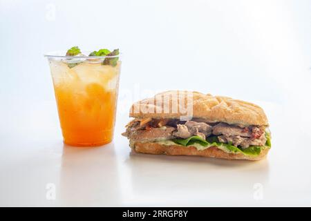 Sandwich au poulet au pesto dans du pain panini avec boisson glacée à la mangue peachy froide. Banque D'Images