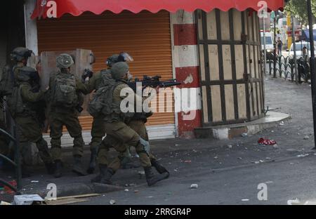 220529 -- HÉBRON, le 29 mai 2022 -- des soldats israéliens pointent leurs armes sur des manifestants palestiniens après une manifestation contre la marche du drapeau dans la ville de Hébron en Cisjordanie, le 29 mai 2022. La marche controversée du drapeau organisée par des groupes israéliens d’extrême droite devrait avoir lieu dimanche pour marquer la Journée de Jérusalem, qui commémore l’unification de la ville après l’annexion par Israël de Jérusalem-est en 1967. Son itinéraire devrait passer par la porte de Damas et le quartier islamique dans la vieille ville. Photo de /Xinhua MIDEAST-HEBRON-PROTEST MamounxWazwaz PUBLICATIONxNOTxINxCHN Banque D'Images