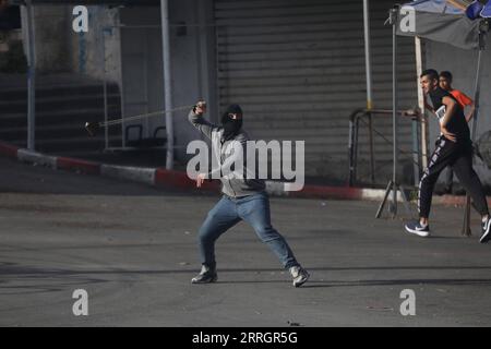 220529 -- HÉBRON, le 29 mai 2022 -- Un manifestant palestinien jette une pierre sur des soldats israéliens à la suite d'une manifestation contre la marche du drapeau dans la ville d'Hébron en Cisjordanie, le 29 mai 2022. La marche controversée du drapeau organisée par des groupes israéliens d’extrême droite devrait avoir lieu dimanche pour marquer la Journée de Jérusalem, qui commémore l’unification de la ville après l’annexion par Israël de Jérusalem-est en 1967. Son itinéraire devrait passer par la porte de Damas et le quartier islamique dans la vieille ville. Photo de /Xinhua MIDEAST-HEBRON-PROTEST MamounxWazwaz PUBLICATIONxNOTxINxCHN Banque D'Images