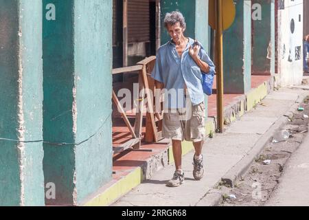 La Havane, Cuba - 3 septembre 2023 : homme cubain senior marchant avec un sac dans le dos sur un trottoir de la ville Banque D'Images