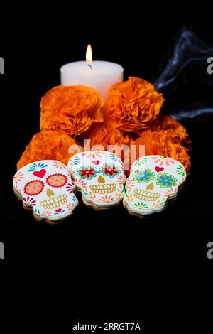 Biscuits avec des formes de catrinas mexicaines et fleurs de souci orange pour célébrer Halloween ou le jour des morts sur fond noir Banque D'Images