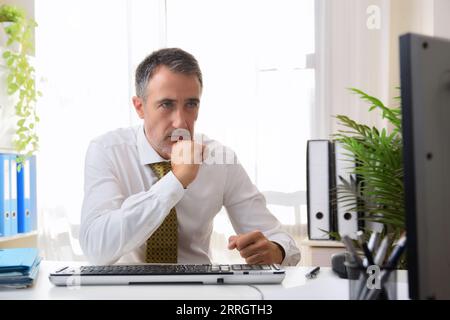 Détail d'un homme d'affaires travaillant sur un ordinateur de bureau regardant l'écran inquiet dans un bureau Banque D'Images