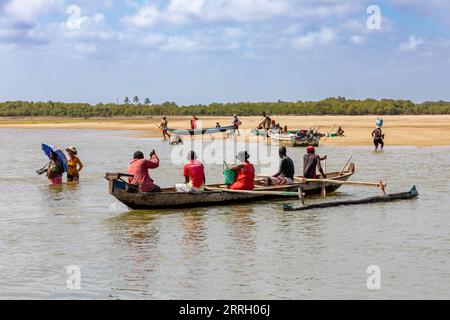 MORONDAVA, MADAGASCAR - 22 NOVEMBRE 2022 : famille malgache dans un bateau traditionnel en bois traversant la rivière à Morondava, Madagascar. Banque D'Images