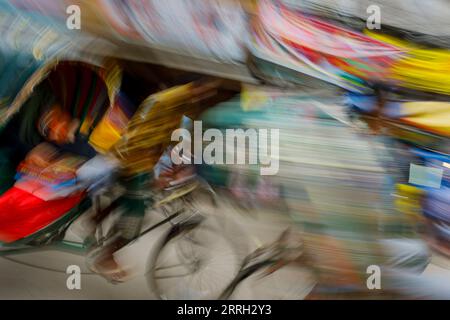 Un taxi à vélo - un pousse-pousse - en mouvement dans les rues animées du Vieux Dhaka au Bangladesh. Dans les rues étroites de Pourim Dhaka, le ricksha reste le deuxième moyen le plus rapide de se déplacer. Le moyen le plus rapide est à pied. Une mauvaise gestion du trafic est un goulot d'étranglement constant pour la circulation et les affaires dans les villes du Bangladesh. Banque D'Images