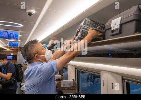 220620 -- CHONGQING, le 20 juin 2022 -- Un passager arrange sa valise à bord du train G52 dans la municipalité de Chongqing, dans le sud-ouest de la Chine, le 20 juin 2022. Avec une longueur totale de 1 068 km, le chemin de fer à grande vitesse Zhengzhou-Chongqing est entré en service lundi. Grâce à la ligne, le temps de trajet de Chongqing à Zhengzhou peut être raccourci d'environ 8 heures à 4 heures 23 minutes à la vitesse maximale, tandis que le temps le plus court de Chongqing à Pékin sera réduit de plus de 20 heures à moins de 7 heures. CHINE-CHONGQING-ZHENGZHOU-CHEMIN DE FER-PLEINE OPÉRATION CN TANGXYI PUBLICATIONXNOTXINXCHN Banque D'Images