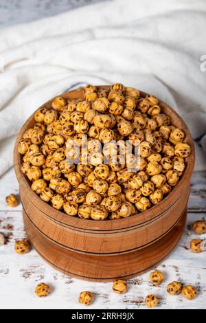 Pois chiches rôtis dans un bol en bois. Pois chiches sur fond de bois blanc Banque D'Images