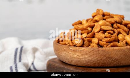 Cacahuètes avec sauce dans un bol en bois. Cacahuètes avec sauce sur fond de bois blanc. Espace de copie. Espace vide pour le texte Banque D'Images