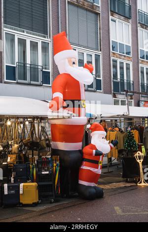 Deux Santa Clause gonflables agitant leurs mains au milieu du marché de rue à Amsterdam Banque D'Images